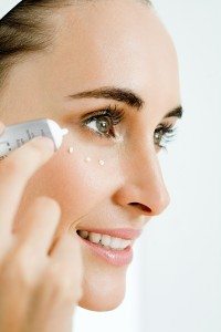 Young woman applying eye cream